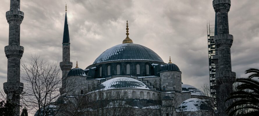 A majestic mosque with snow-covered domes under a cloudy sky